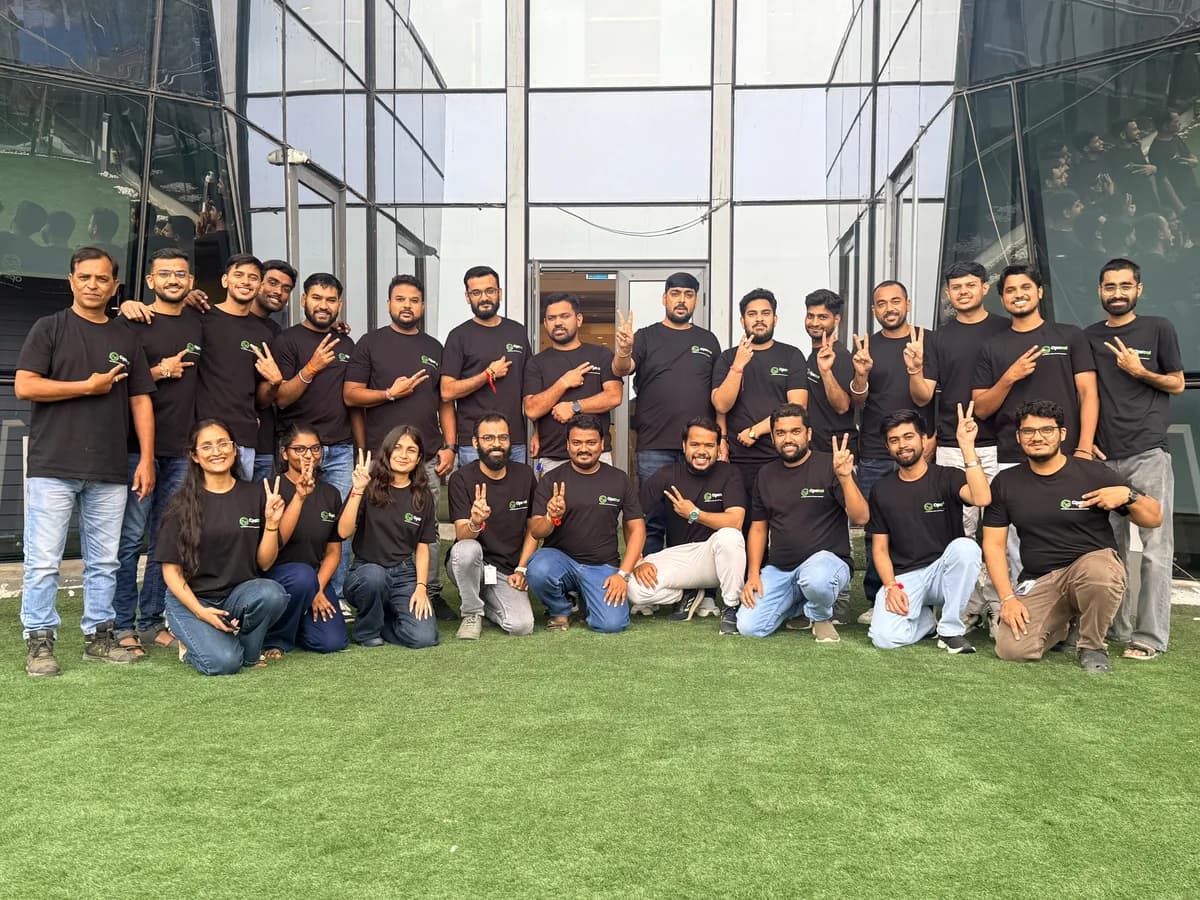 Opstral team members in branded t-shirts flashing victory signs outside the office